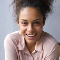 Smiling model leaning forward and wearing a pink shirt