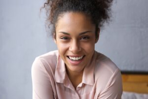 Smiling model leaning forward and wearing a pink shirt